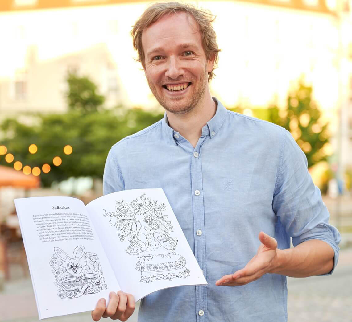 自著のマンガ技法書を手にするマキシム講師。ドイツで出版された描き方の本